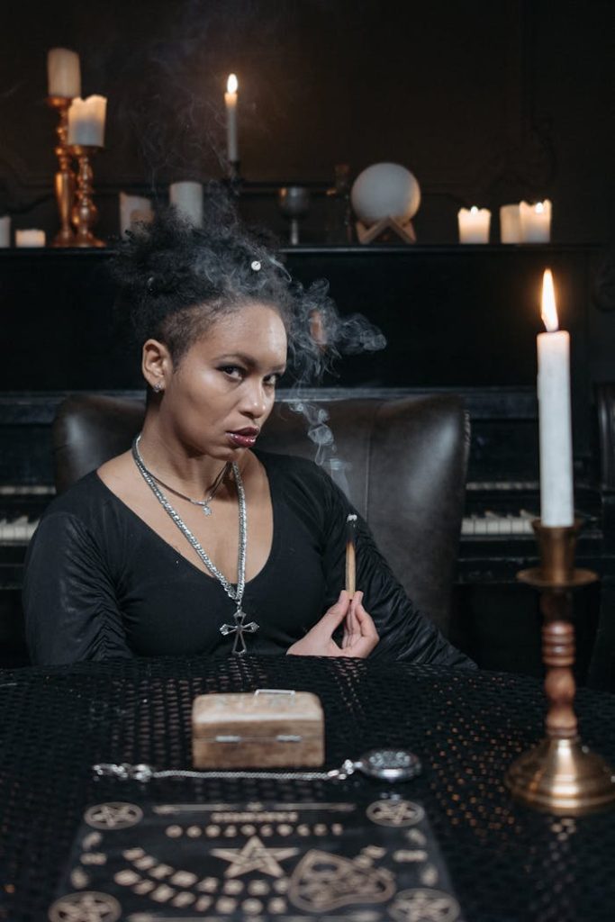 a-woman-holding-an-incense-stick-7278782 A woman in a mystical setting performing a spiritual ritual with candles and incense.