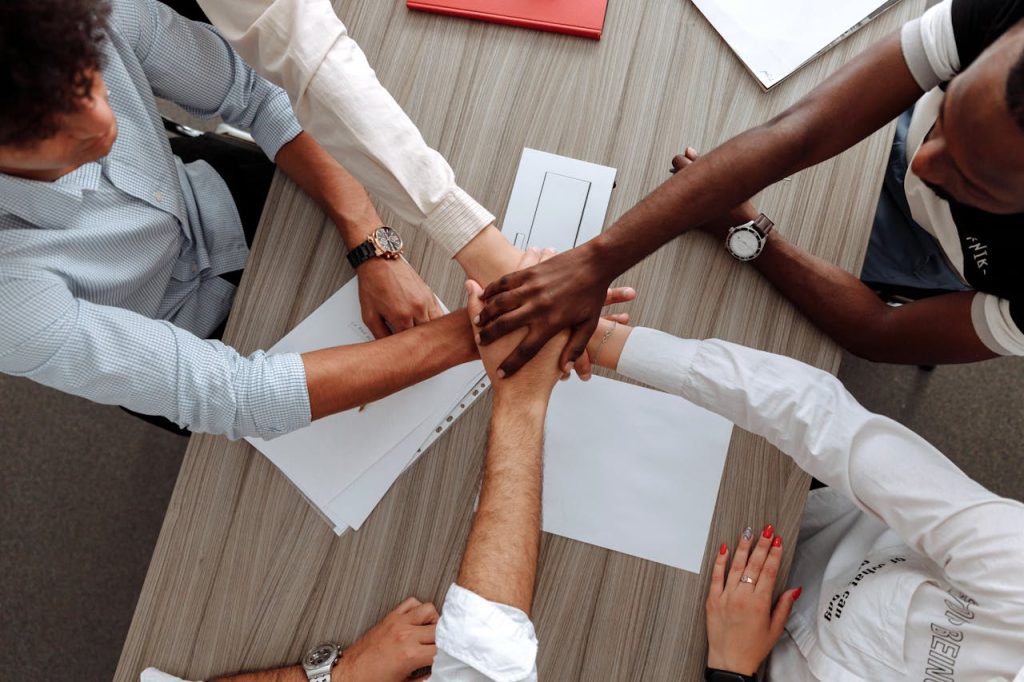 man-and-woman-holding-each-other-s-hands-as-a-team-5256816 A diverse group of adults join hands in an office, symbolizing teamwork and cooperation.